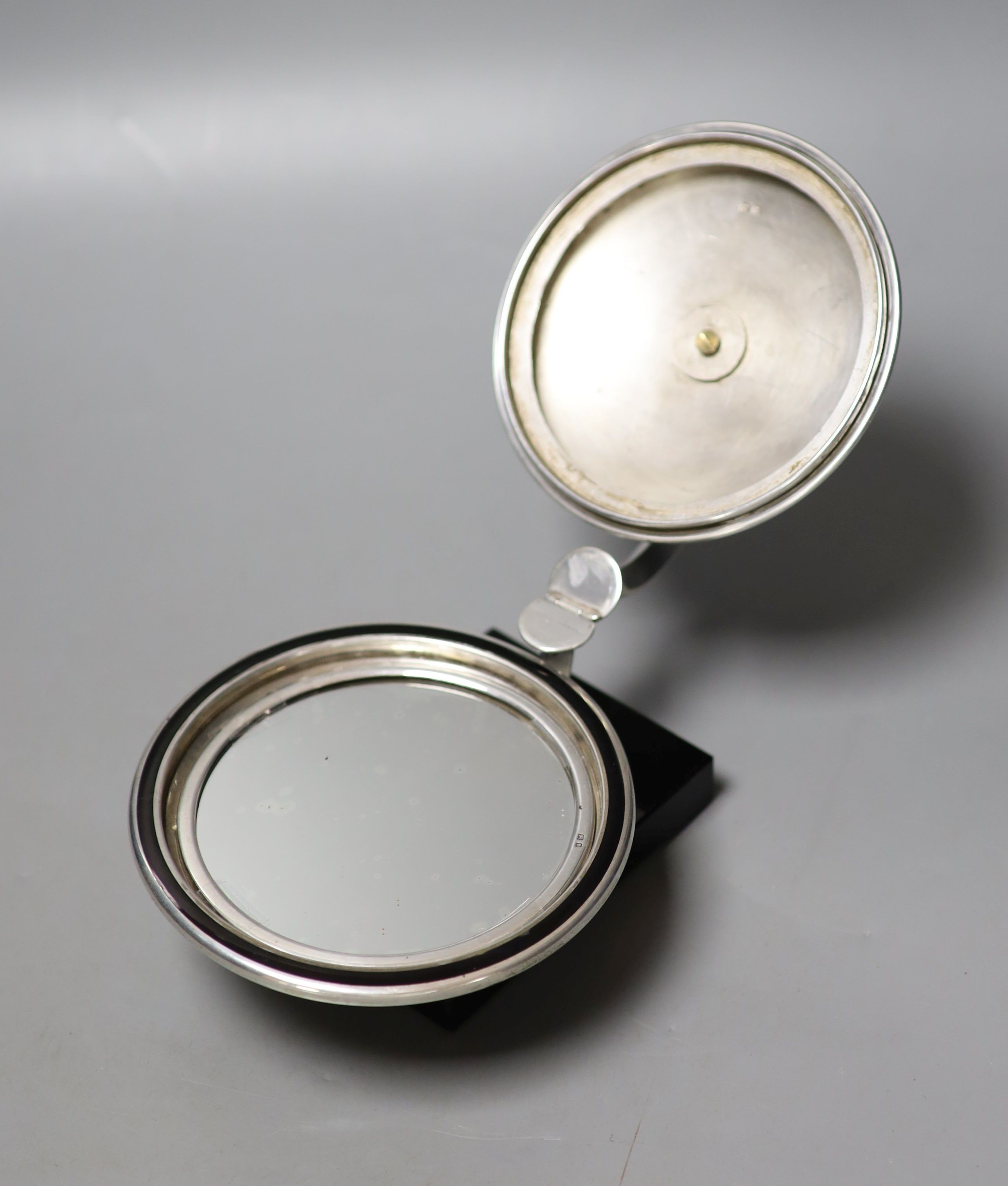 An unusual Art Deco engine turned silver and black enamel circular compact, with support arm, on black onyx? base (a.f.), Cohen & Charles, circa 1930, height 9.5cm.